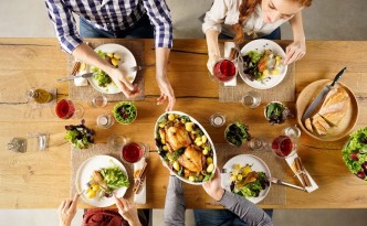 56370745 - top view of man passing food bowl to friend. high angle view of happy young friends eating together at home. happy men and women having lunch with roasted chicken.