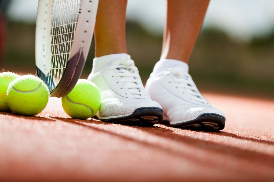 15541608 - legs of athlete near the tennis racket and balls